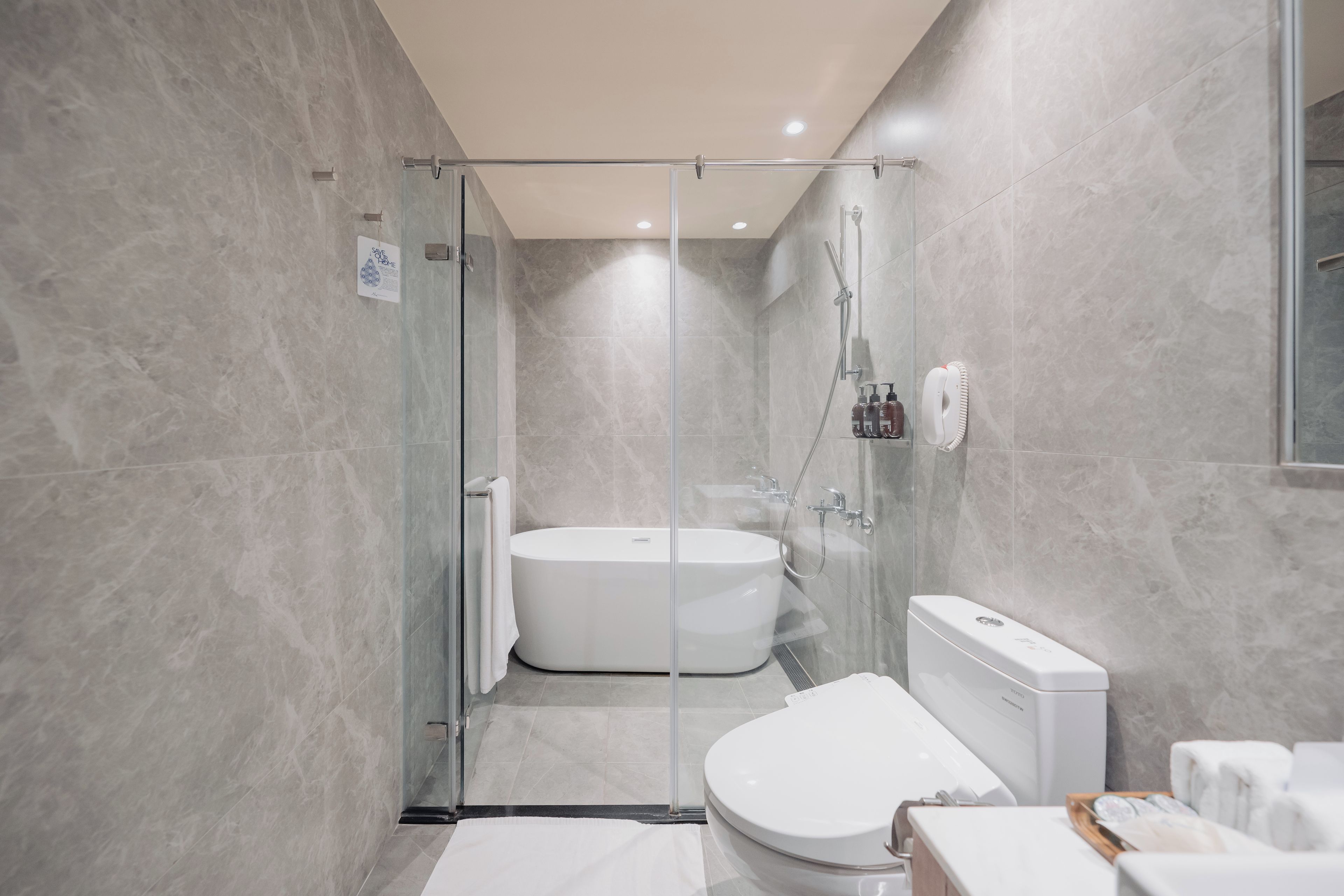 A modern bathroom with a glass-enclosed shower, a freestanding bathtub, and a toilet.