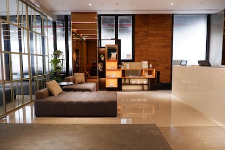 A modern hotel lobby with a sofa, a reception desk, and a large window with a view.
