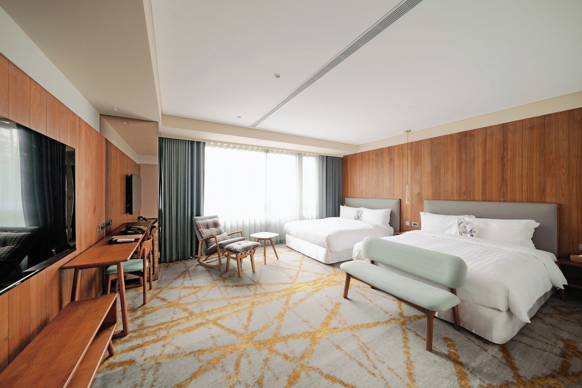 A hotel room with a bed, a desk, a chair, a television, and a window with curtains.
