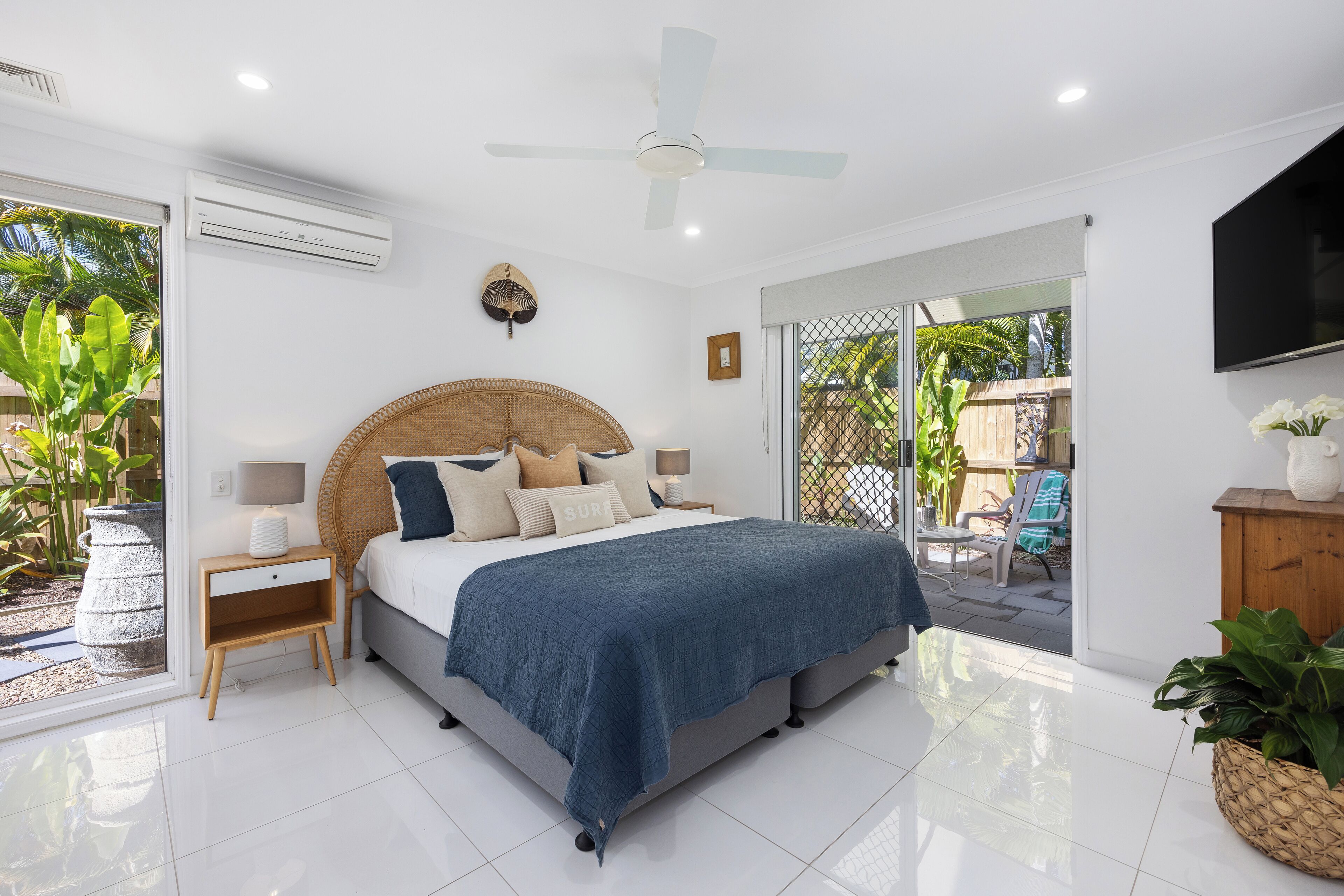 A bedroom with a bed, bedside tables, a ceiling fan, and a TV.