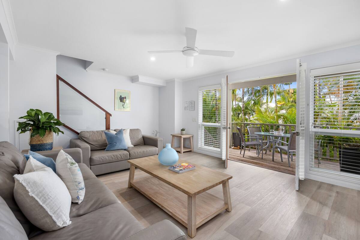 Un salon moderne avec un canapé, une table basse et un ventilateur de plafond.