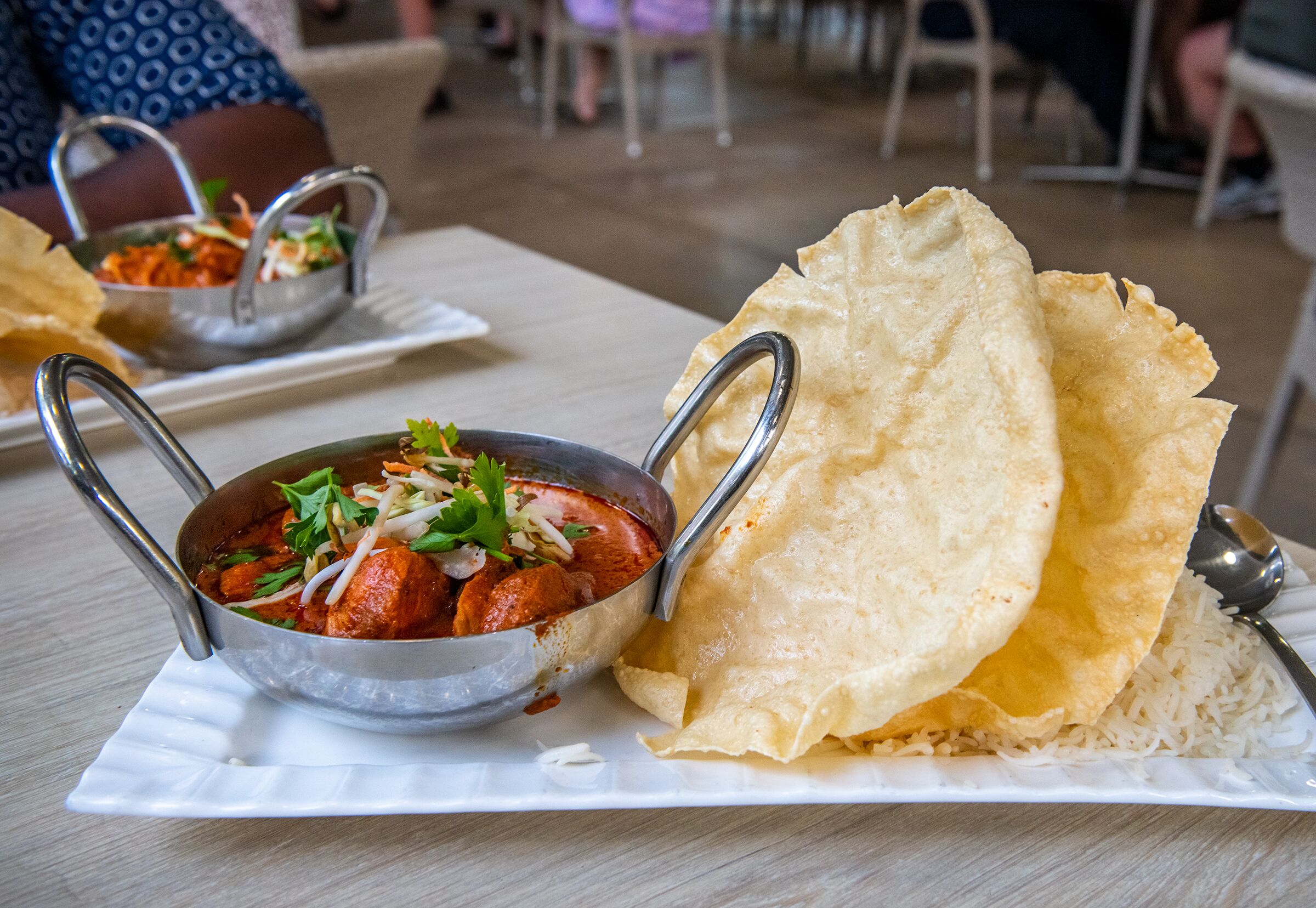 Un plato blanco con curry y pan plano.