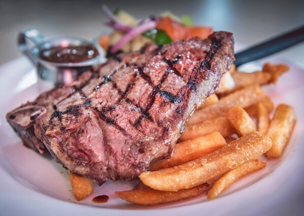 A steak with grill marks, accompanied by French fries and a side salad. - Knotts Crossing Resort (Katherine)