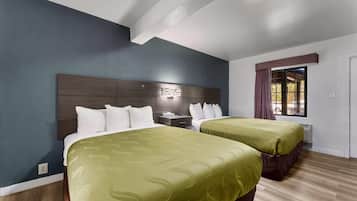 A hotel room with two beds, a nightstand, a window with curtains, and a ceiling light.