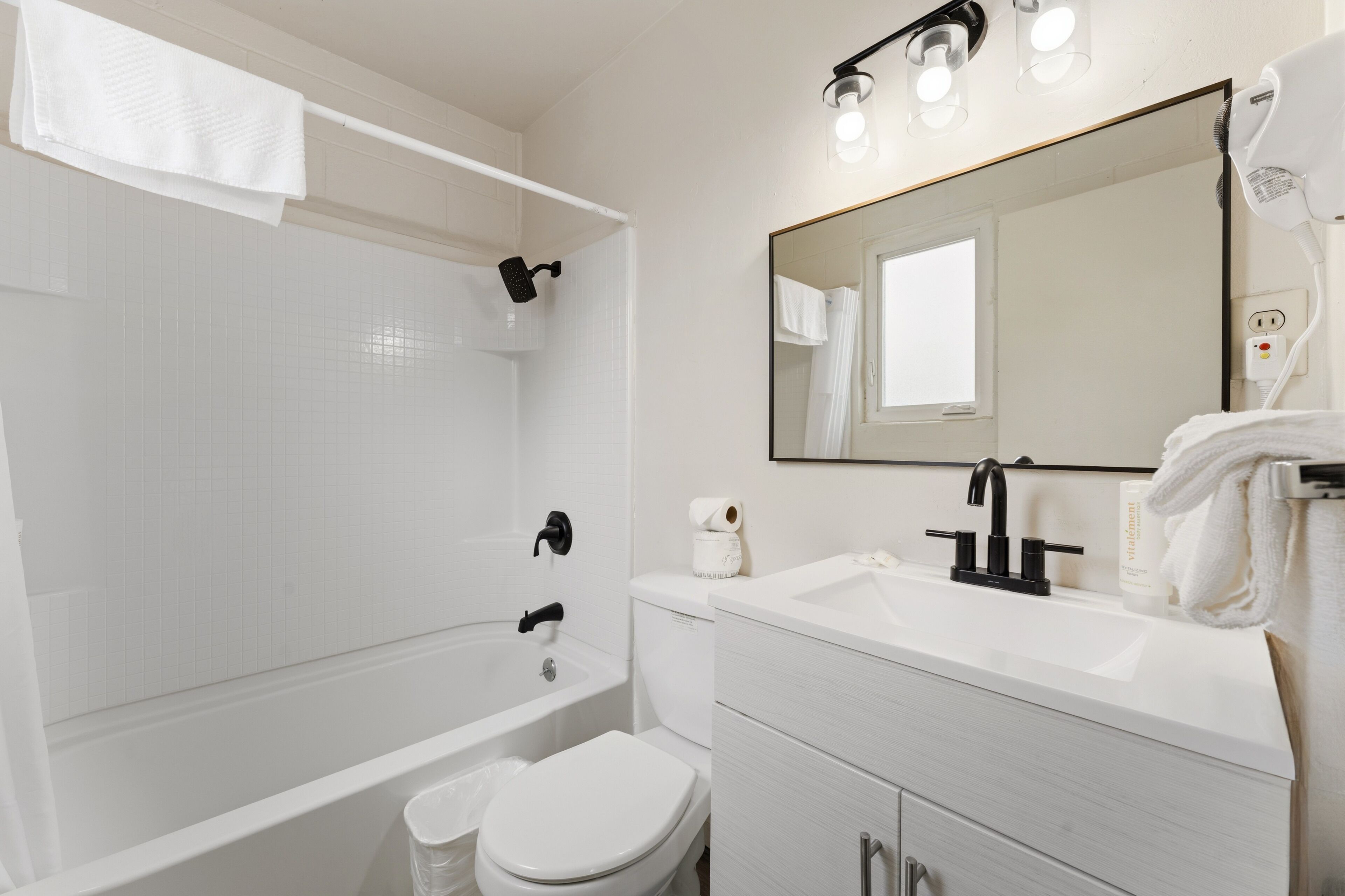 A modern bathroom with a bathtub, toilet, sink, and a large mirror.