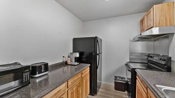 A kitchen with a microwave, toaster, refrigerator, stove, and wooden cabinets.