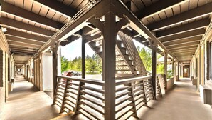 Un pont piétonnier couvert, doté d’une allée centrale, de garde-corps en bois et offrant une vue sur la verdure environnante.