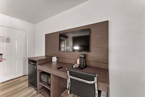 Una kitchenette compacta con microondas, cafetera y un refrigerador pequeño.