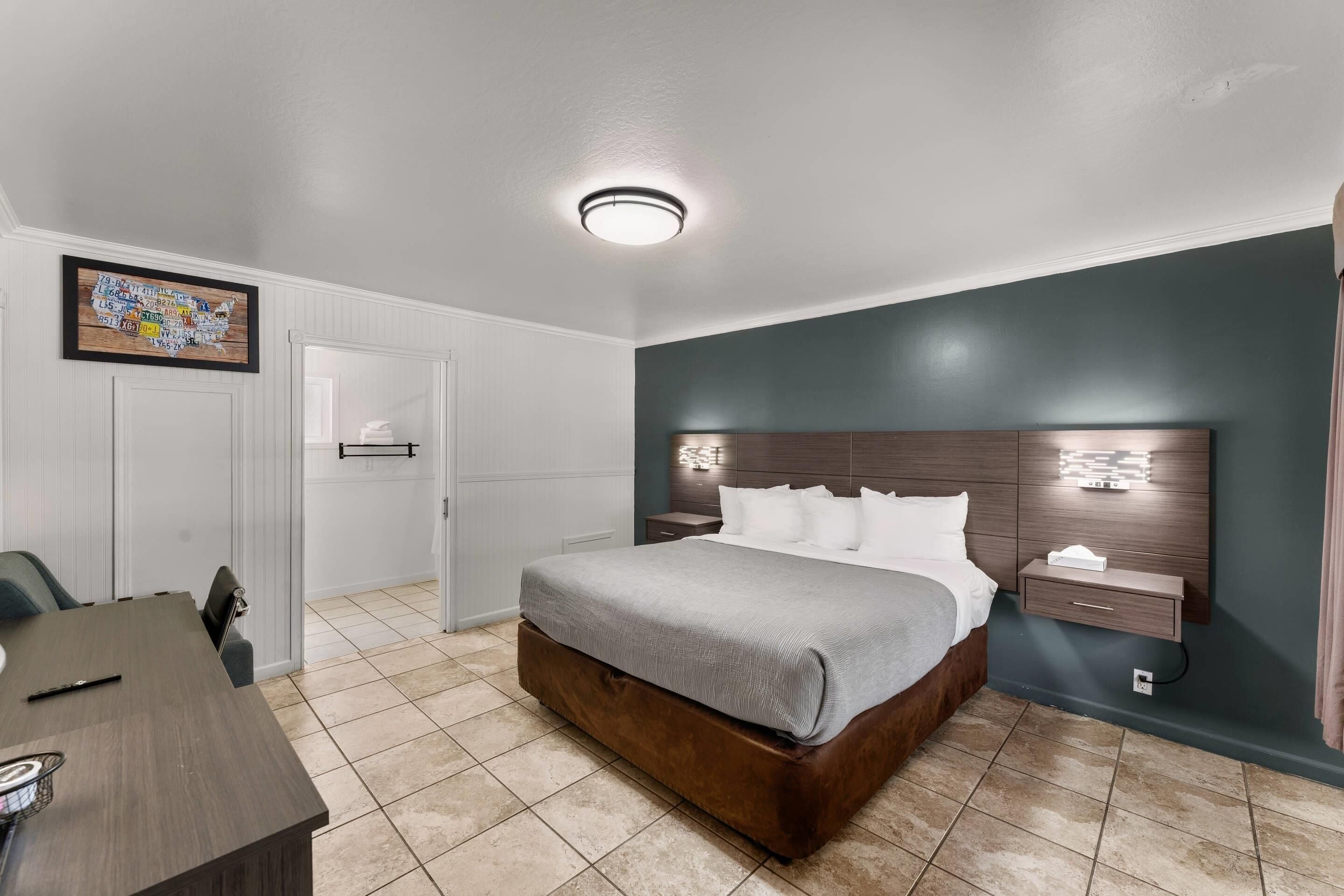 Une chambre à coucher comprenant un lit, une table de chevet, une commode et un bureau avec des chaises.