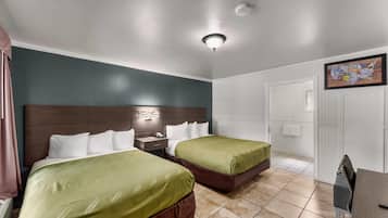 Habitación de hotel con dos camas, una mesita de noche, un escritorio y una silla.