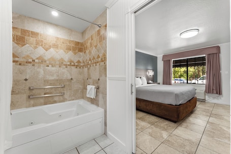 A bathroom with a bathtub, shower, and tiled walls.. Econo Lodge Inn & Suites Heavenly Village Area