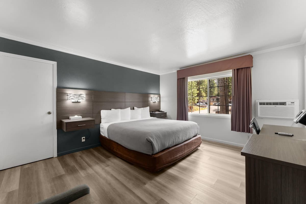 A modern bedroom with a bed, bedside table, nightstand, and a window with curtains.
