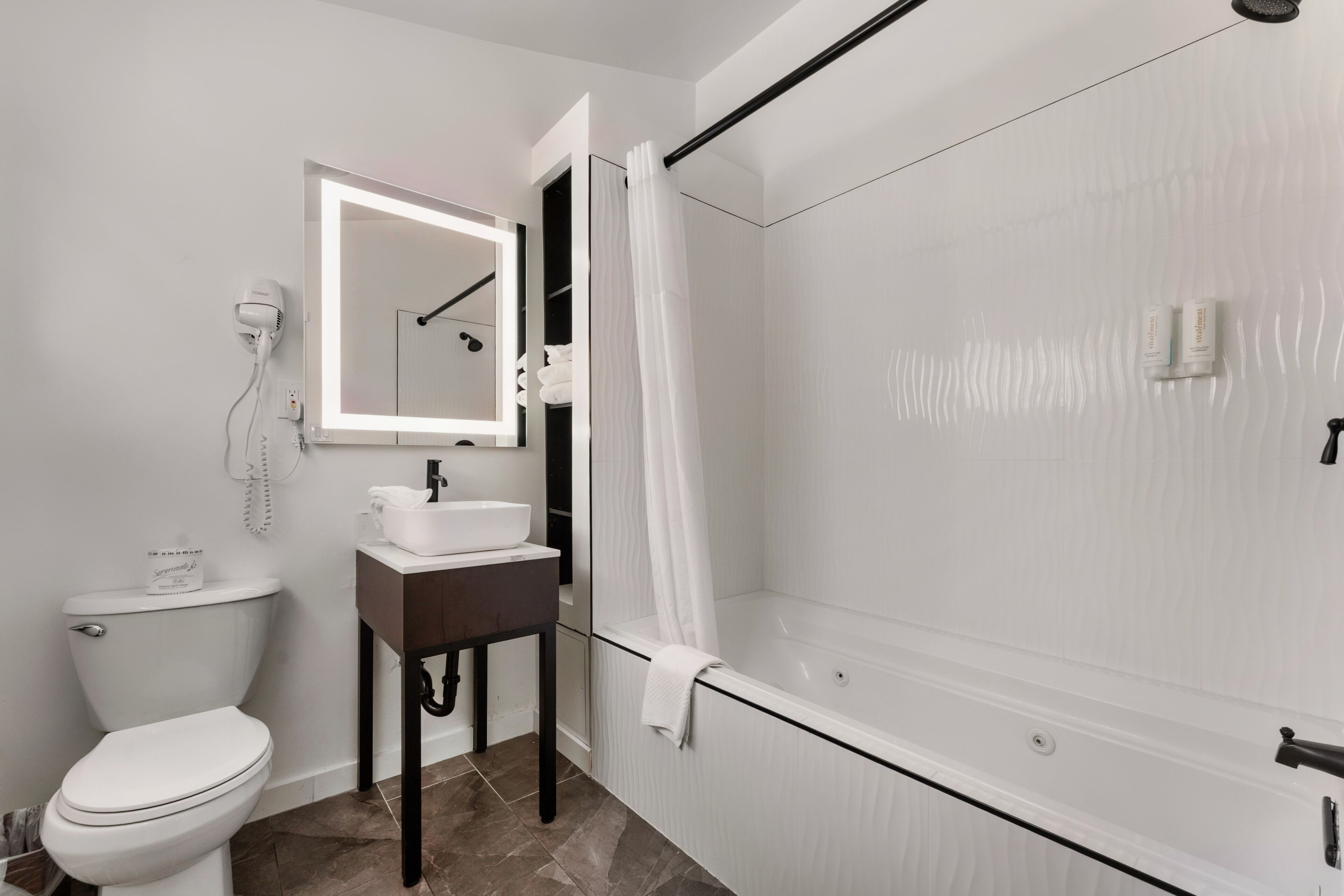 A bathroom with a toilet, sink, mirror, shower, and a towel rack.