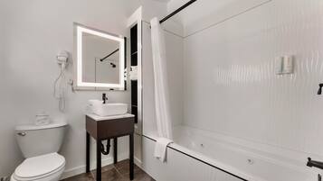 A bathroom with a toilet, sink, mirror, shower, and a towel rack.