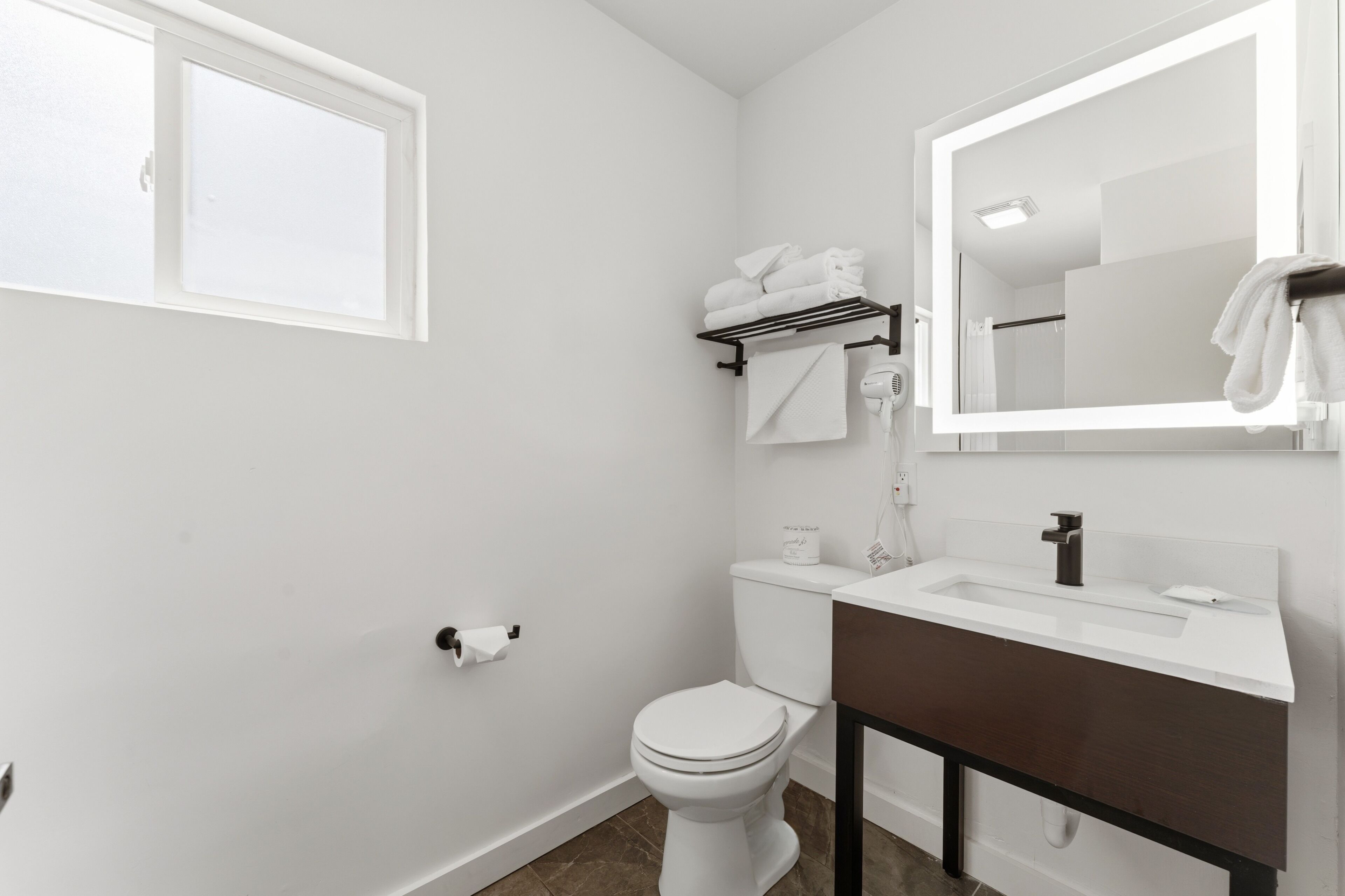 A bathroom with a white toilet, a sink with a mirror, and a towel rack.