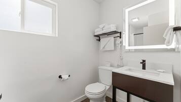 A bathroom with a white toilet, a sink with a mirror, and a towel rack.