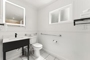 A bathroom with a white sink, toilet, and mirror. There is a window above the toilet and a towel rack on the wall. - Econo Lodge Inn & Suites Heavenly Village Area (South Lake Tahoe)