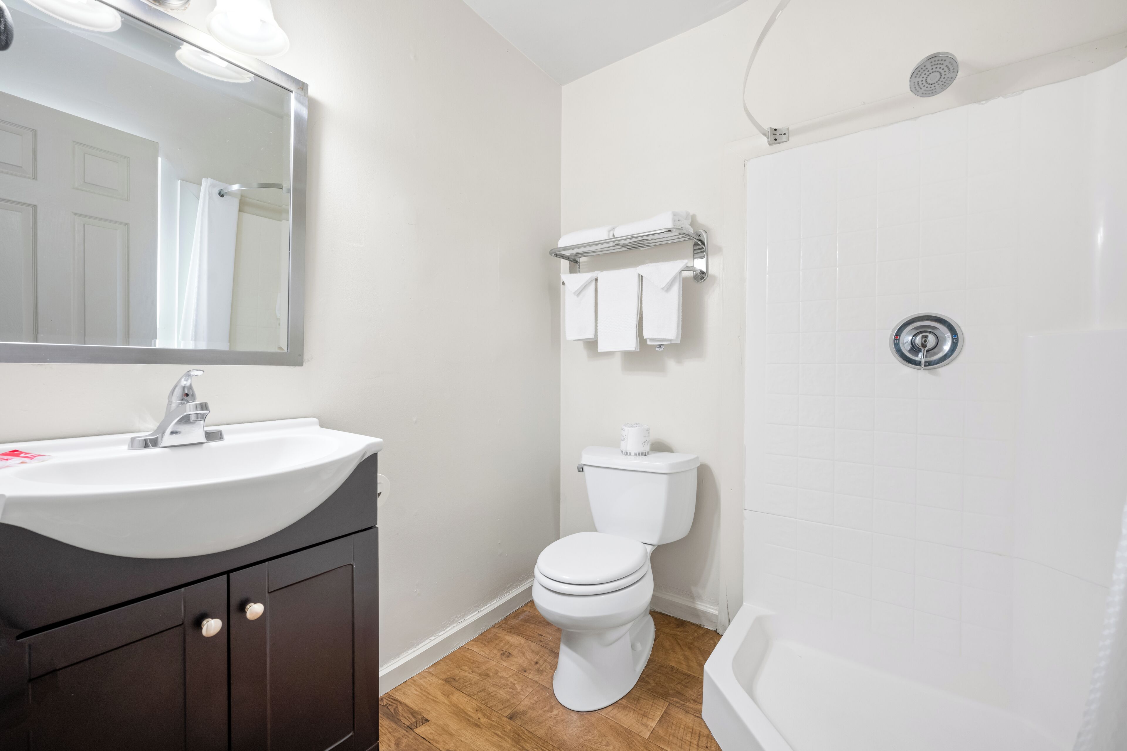 A bathroom with a sink, mirror, toilet, and bathtub.