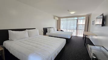 Habitación de hotel con dos camas, un escritorio y una televisión.