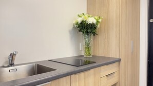 A modern kitchen with a double sink, wooden cabinets, and a vase with flowers on the countertop. - Bluewater Hotel  (Napier)