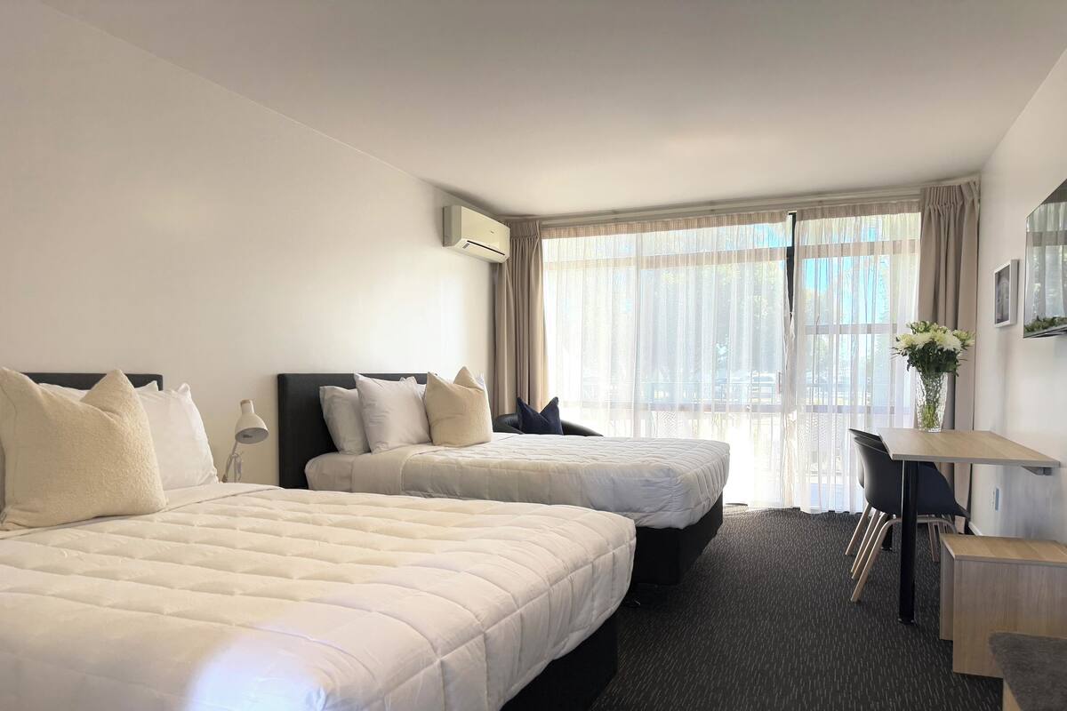Una habitación de hotel con dos camas, un escritorio y una silla.