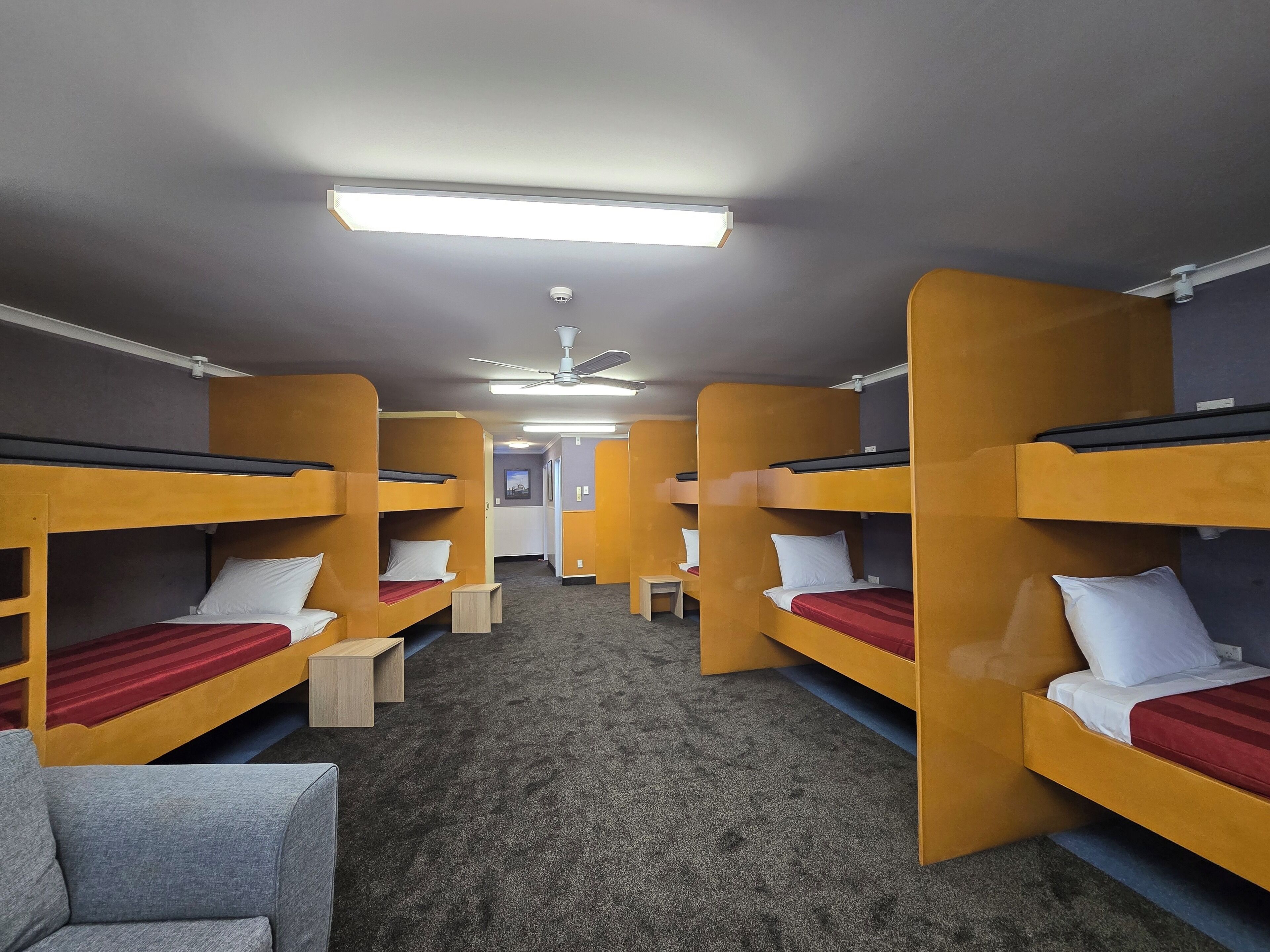 Un dormitorio con literas, un escritorio pequeño y un ventilador de techo.