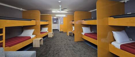 Un dormitorio con literas, un escritorio pequeño y un ventilador de techo.