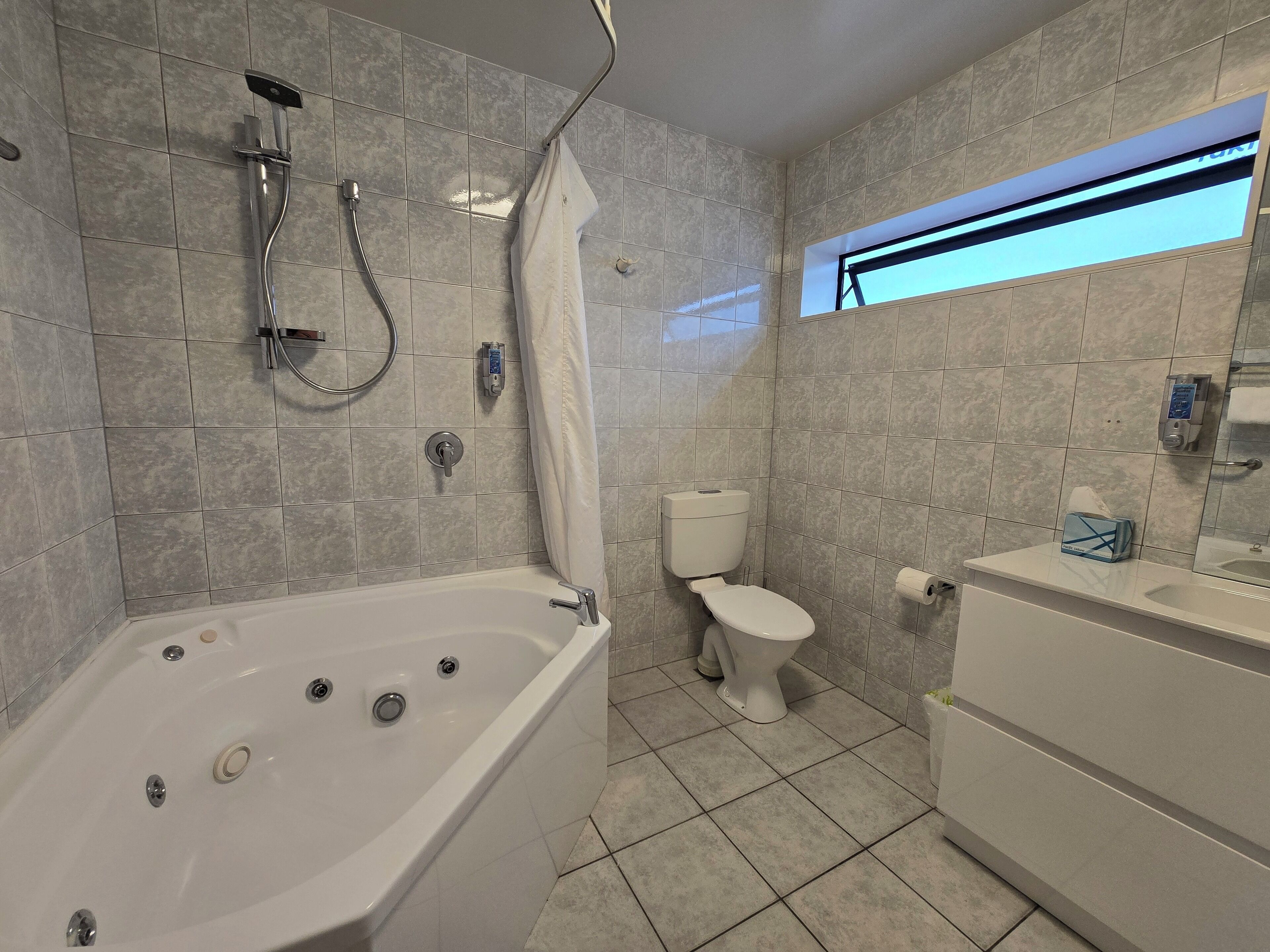 A modern bathroom with a bathtub, toilet, and sink.