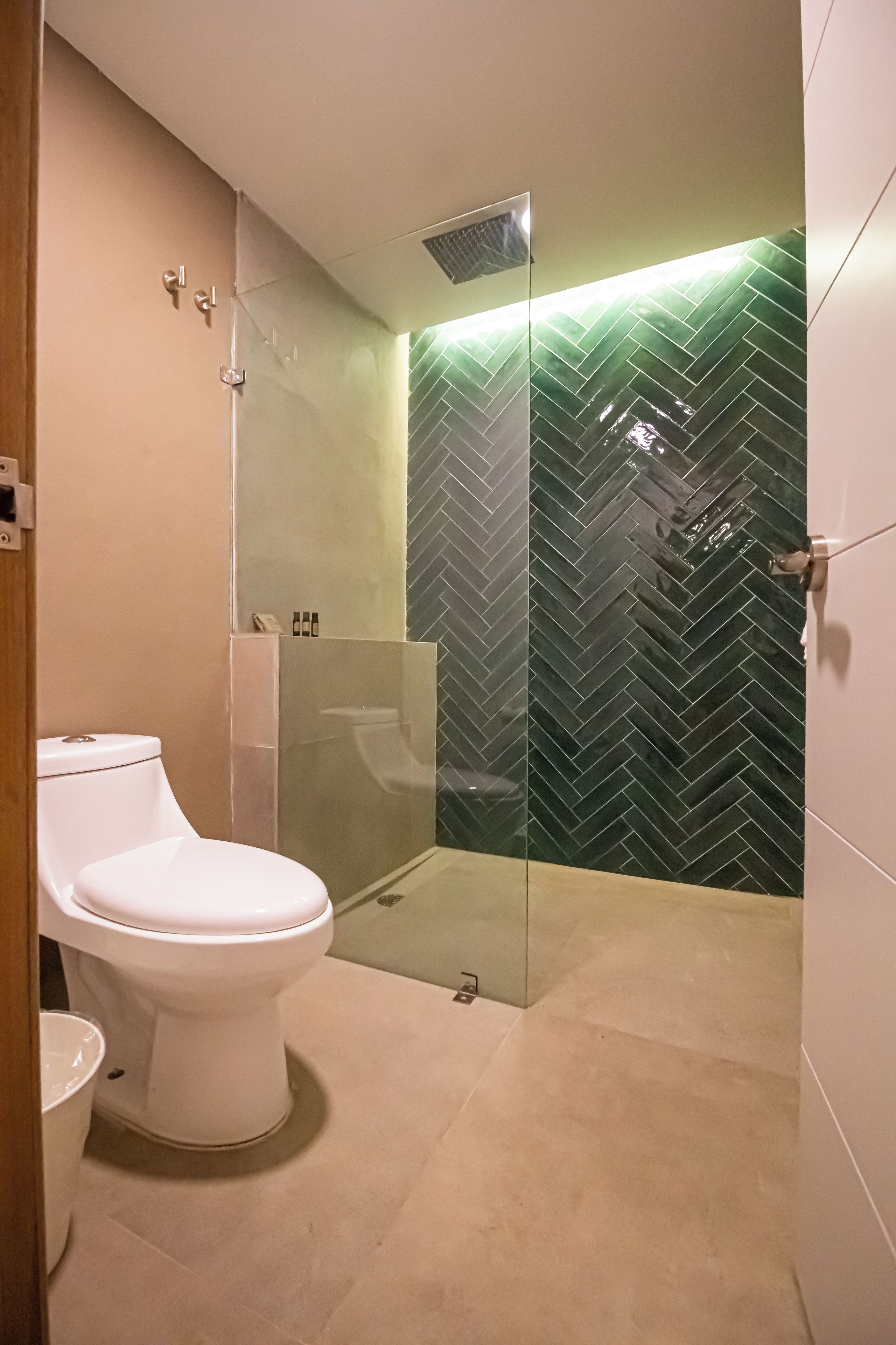 Une salle de bain moderne avec des toilettes, une douche en verre et un mur orné d’un motif en chevrons.