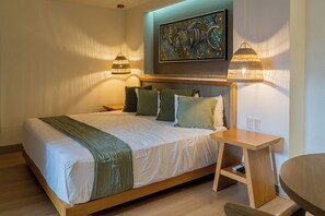 Une chambre à coucher moderne avec un grand lit, deux lampes de chevet, une petite table et un tableau au mur.