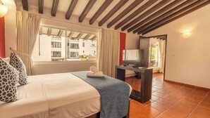 Una habitación de hotel con una cama, un televisor y un ventanal con cortinas.