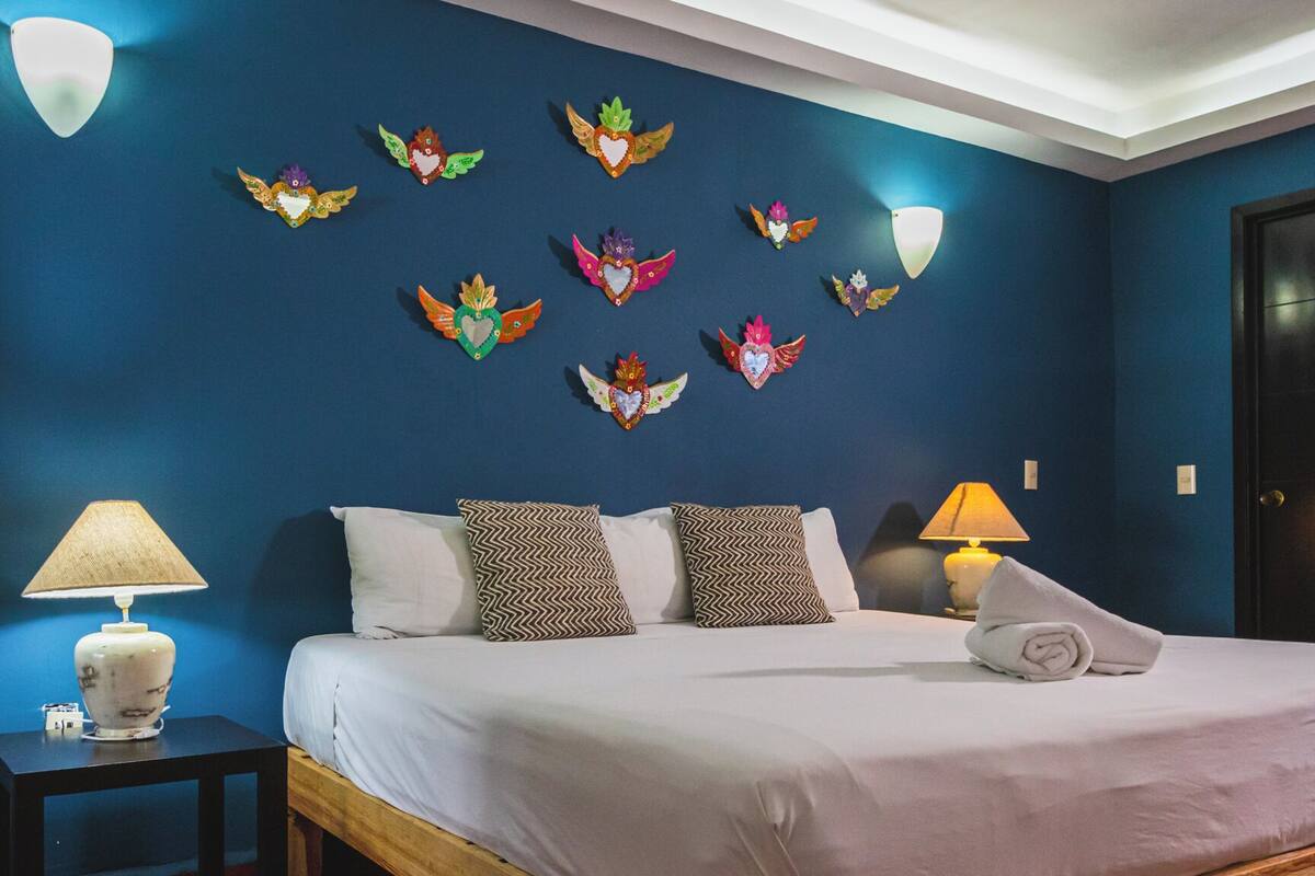 A bedroom with a bed, two nightstands, a lamp, and decorative wall art.