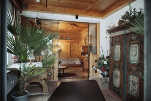 A wooden interior with a sofa, a cabinet with clocks, and a potted plant. - LUMA Stubai Aparthotel (Neustift Im Stubaital)