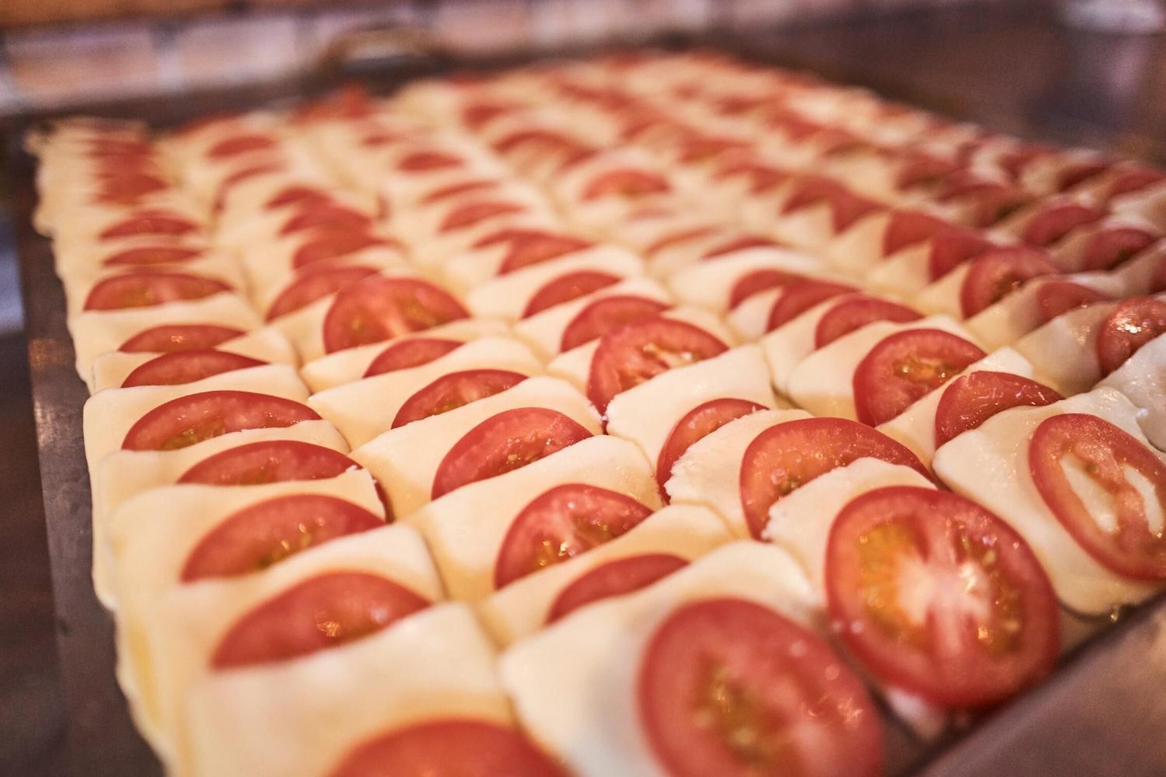 A tray of baked goods with tomato slices.