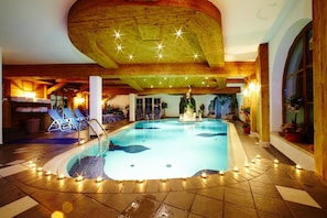 An indoor swimming pool with lounge chairs and a decorative fountain. - LUMA Stubai Aparthotel (Neustift Im Stubaital)