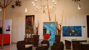 A lobby with wicker furniture, a chandelier, and artwork on the walls. - Zar Colima (Cuauhtémoc)