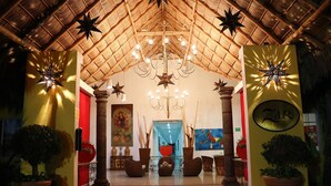 A lobby with a thatched roof, a chandelier, and potted plants. - Zar Colima (Cuauhtémoc)