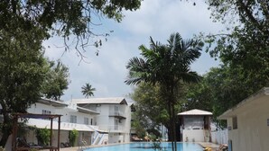 Uma área de piscina com degraus que levam à piscina, cercada por edifícios e árvores.