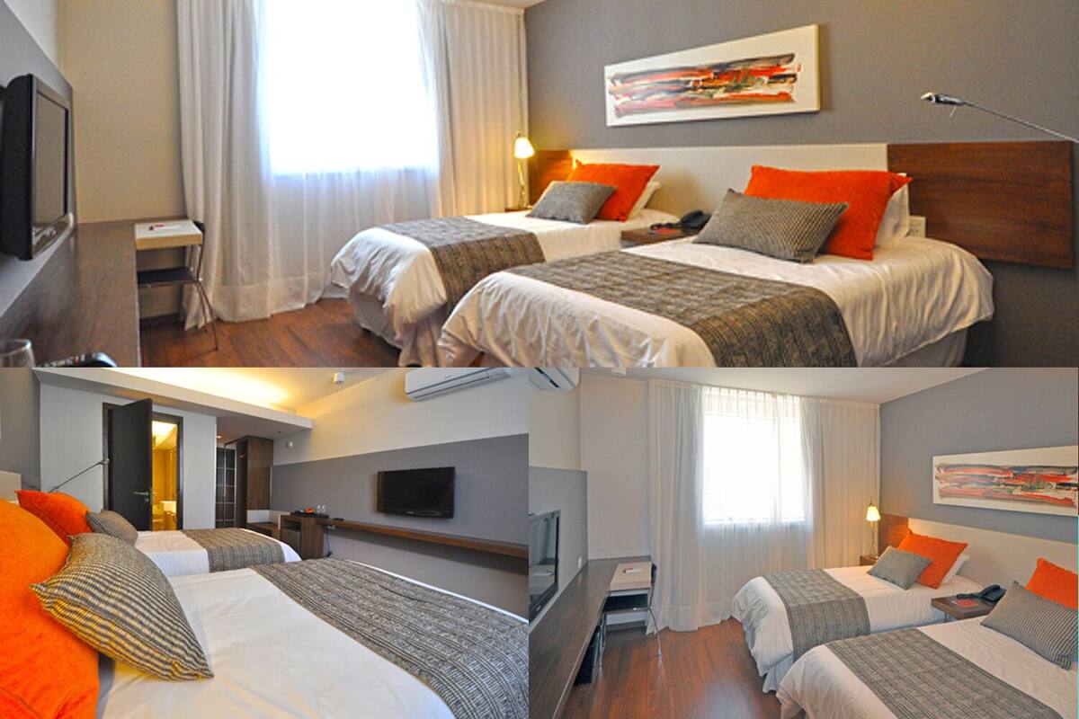 Una habitación de hotel con dos camas, un televisor, un escritorio y un cuadro en la pared.
