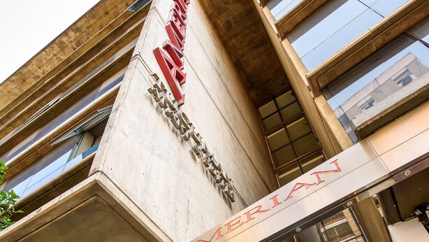 Een gebouw met een opvallend bord waarop 'AMERICAN' en 'TUCUMAN APART & SUITES' staat, wat een hotel of accommodatie aangeeft.