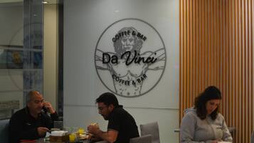 A coffee shop interior with round tables and chairs, a logo on the wall, and a wooden slat design on the right.