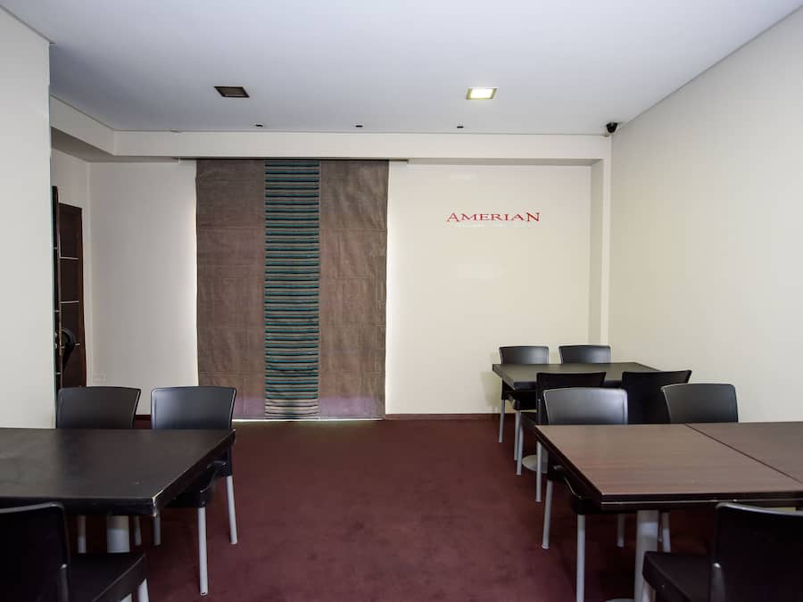 A conference room with a long table and several chairs, a large sign reading "AMERICAN," and a patterned wall divider.