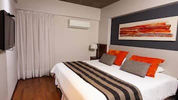 Habitación de hotel con una cama grande, un televisor de pantalla plana, un ventilador de techo y una ventana con cortinas.