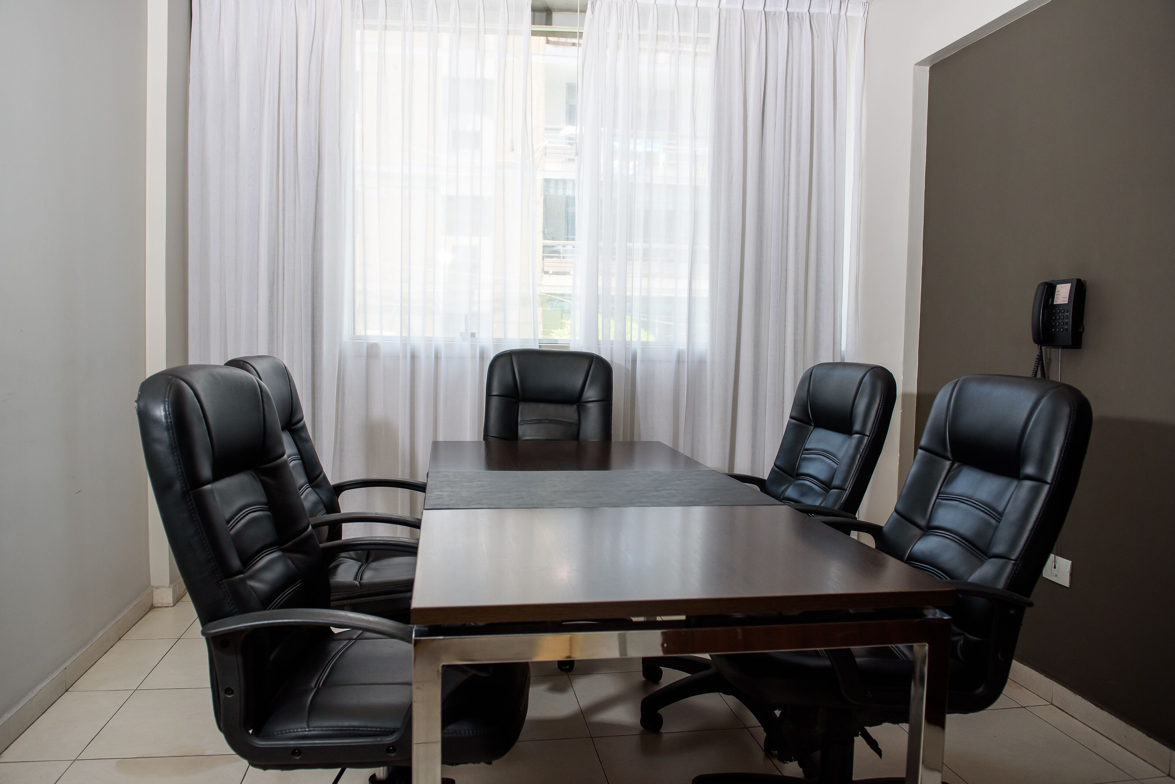 Un salón de conferencias con una larga mesa y cuatro sillas de cuero negro.