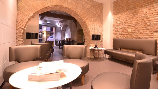 A modern lounge with leather seating, a stone archway, and a stone wall. - Hotel De Rome (Rome)
