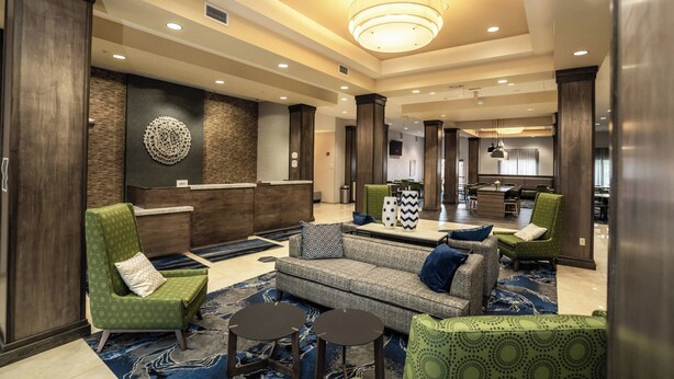 A hotel lobby with a reception desk, seating area with sofas and chairs, and a dining area in the background. - Fairfield Inn & Suites by Marriott Kearney (Kearney)