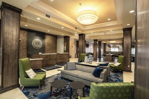 A hotel lobby with a reception desk, seating area with sofas and chairs, and a dining area in the background. - Fairfield Inn & Suites by Marriott Kearney (Kearney)