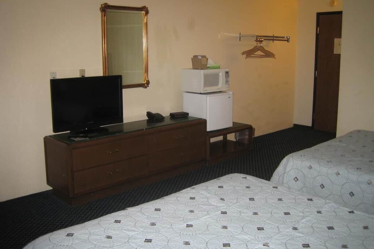 A hotel room with a TV on a dresser, a microwave, a small table, and two beds.