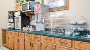 Una kitchenette con cafetera, microondas, tostadora y una vitrina con productos de panadería.