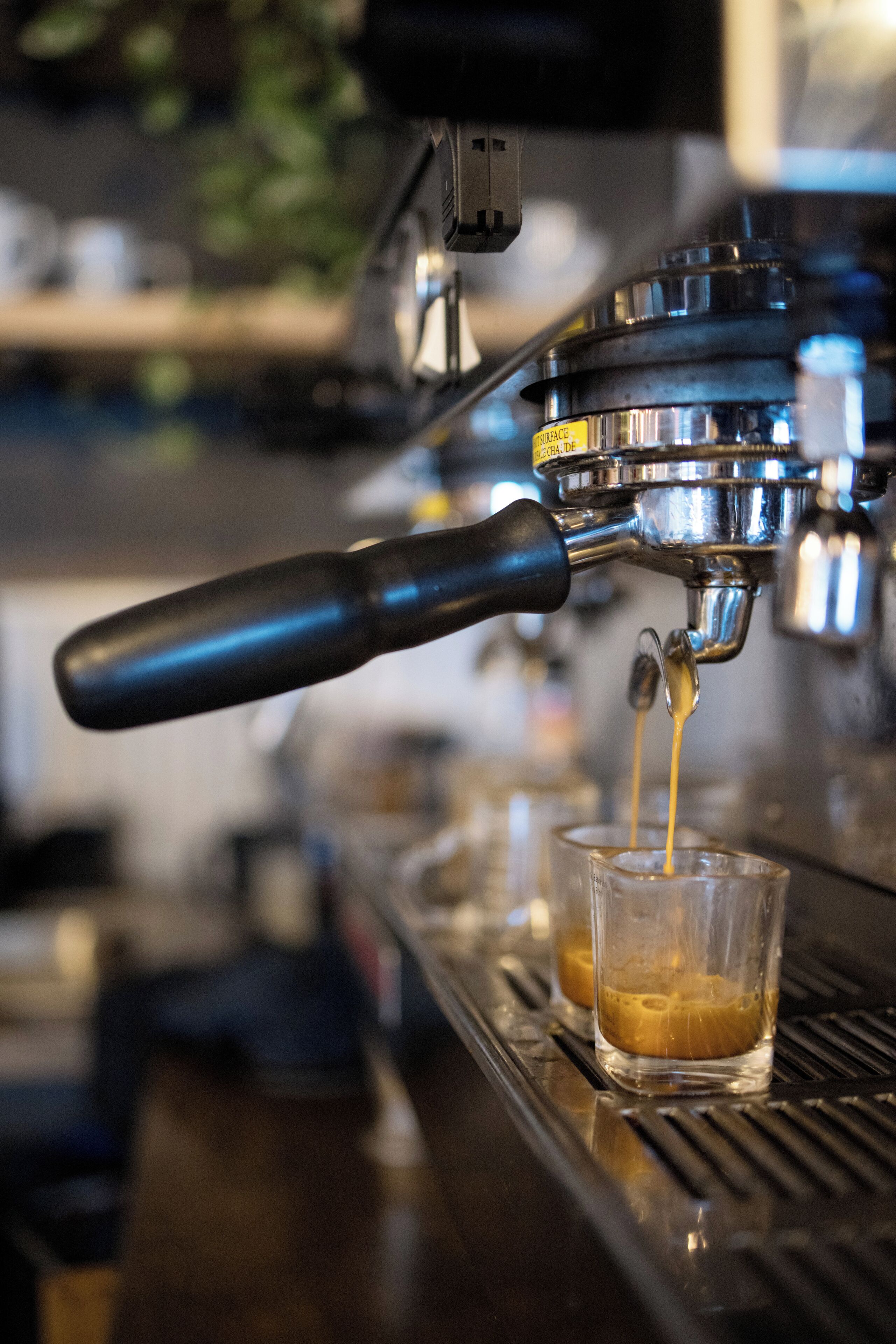 Primer plano de una máquina de café sirviendo un espresso en una taza de vidrio.